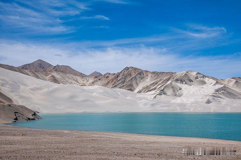 帕米尔高原的白沙湖，是蓝与白交织的高原幻境 。
湖畔的白沙山银白细腻，如凝固的浪