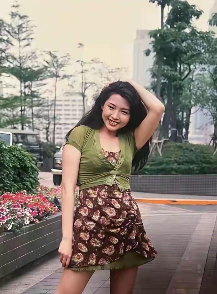 这位姑娘在公园里拍照，笑容甜美。很久没见了，非常低调。这应该是90年代的一张照片