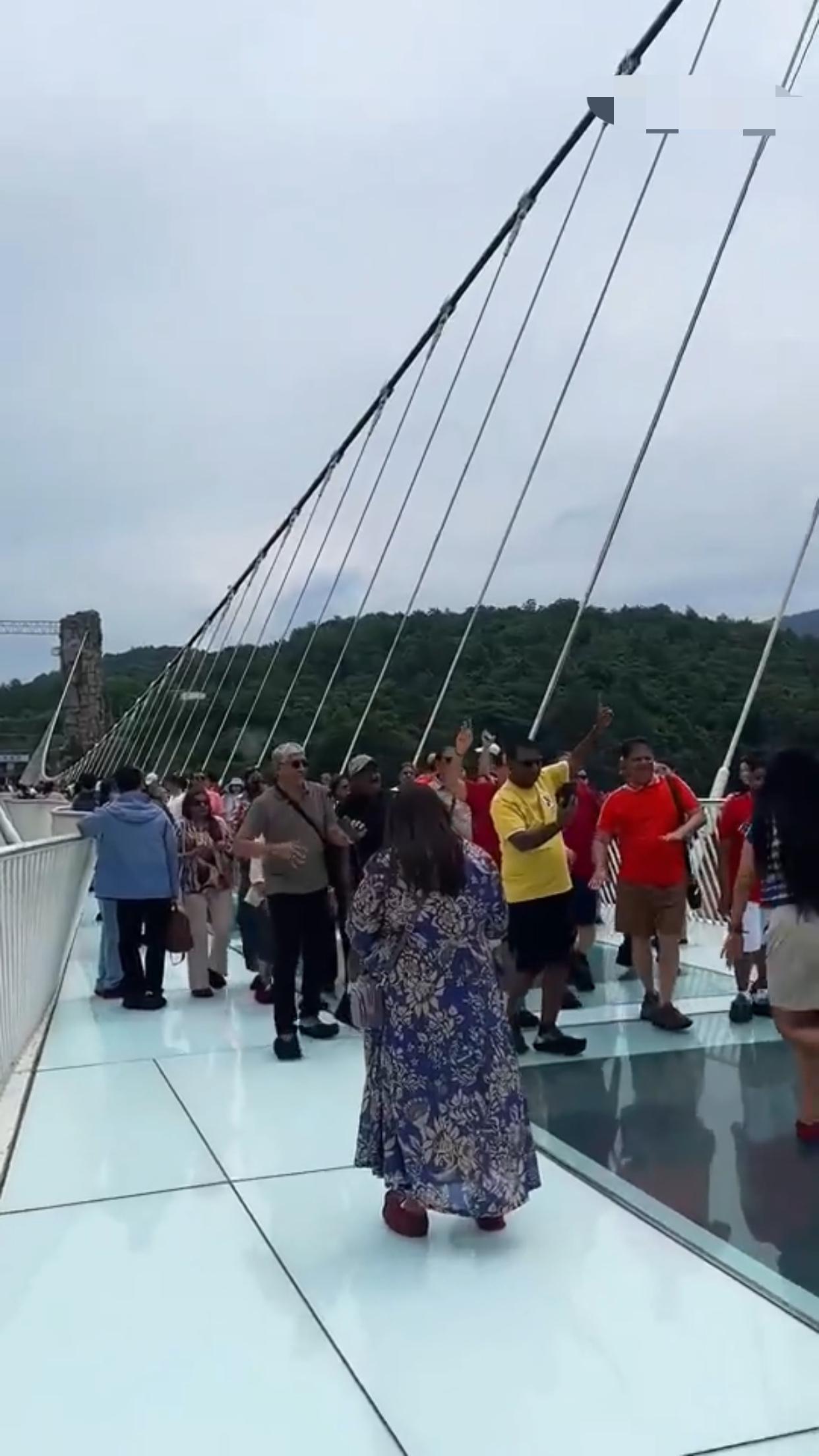 一群印度游客在湖南张家界风景区的玻璃栈桥上跳起舞来，看起来有点危险，感觉现在在中