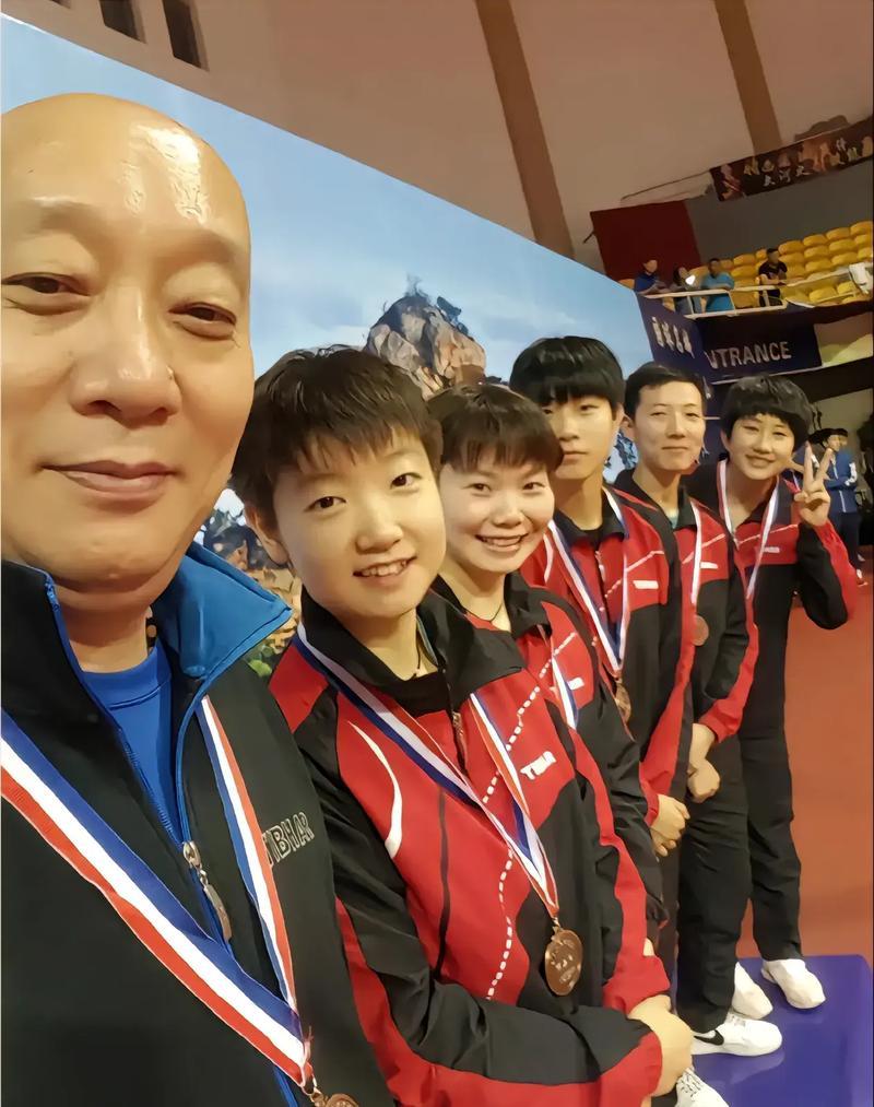 5位挂着金牌的乒乓球员与教练合照：我只认出了凤眼如虹的孙颖莎，满面春风的何卓佳和