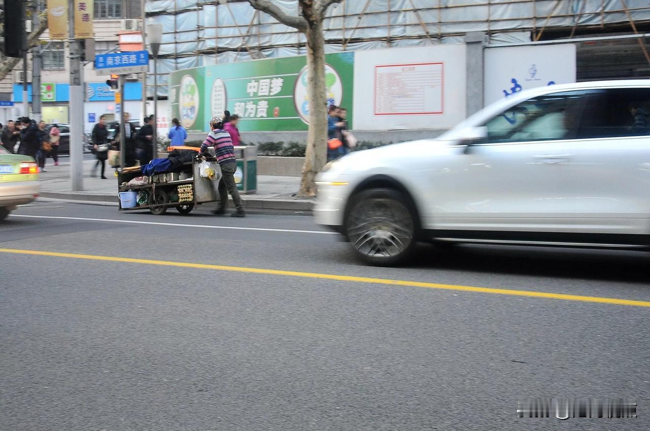 在南京西路上，一辆满塞垃圾的手推车，与玛莎拉蒂豪车并驾齐驱，可走的不是一根道，贫