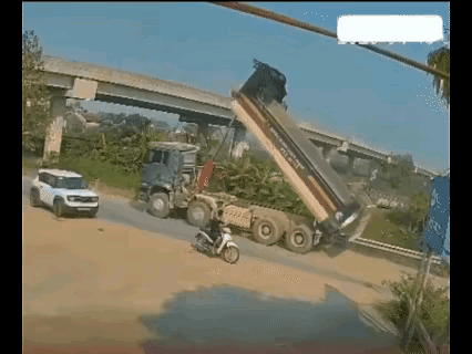 这个二货！车厢一直立着不知道吗？没放下就敢在路上开，而且还敢在立交桥下直接往过撞