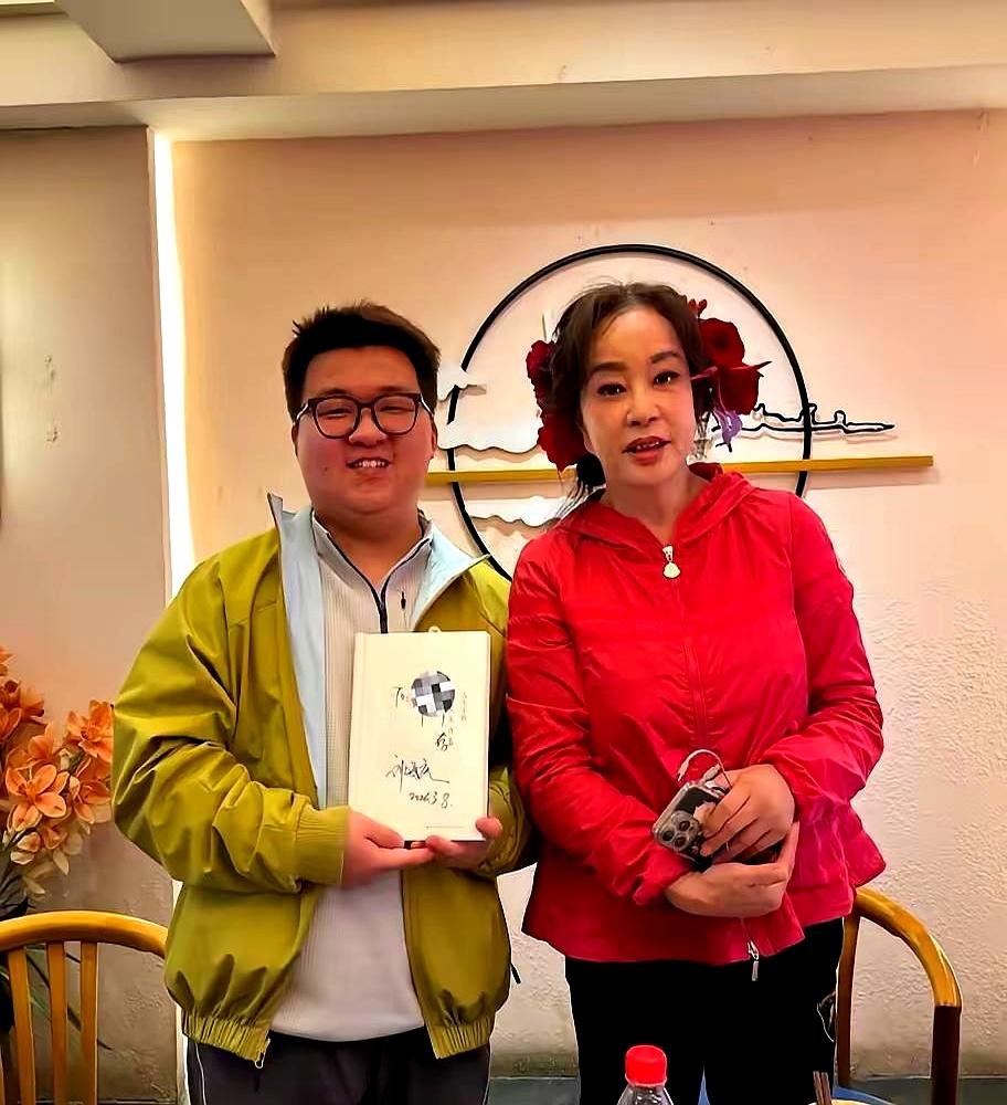 75岁刘晓庆回重庆吃火锅，保安围成人墙开路。
她穿黑西装别着大红花，逛南滨路钻