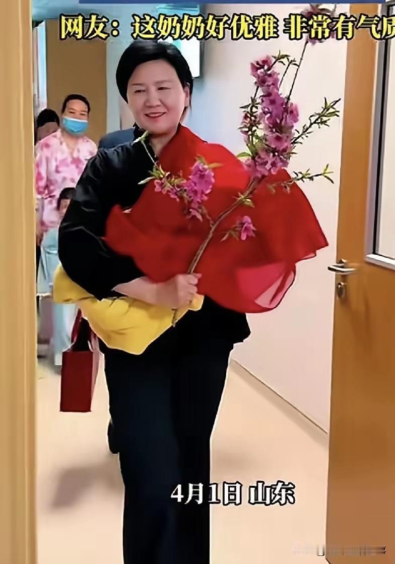 优雅！
红色包裹喜庆，手持带花苞桃枝辟邪纳福，抱着孙子举止大方轻盈，发自内心的喜
