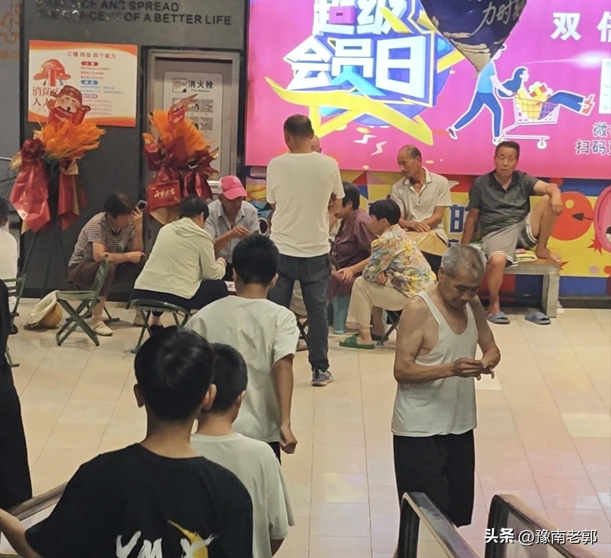 在河南驻马店泌阳一商场里边，出现了许多搬着小马扎拿着防潮垫在这里避暑的百姓。
 