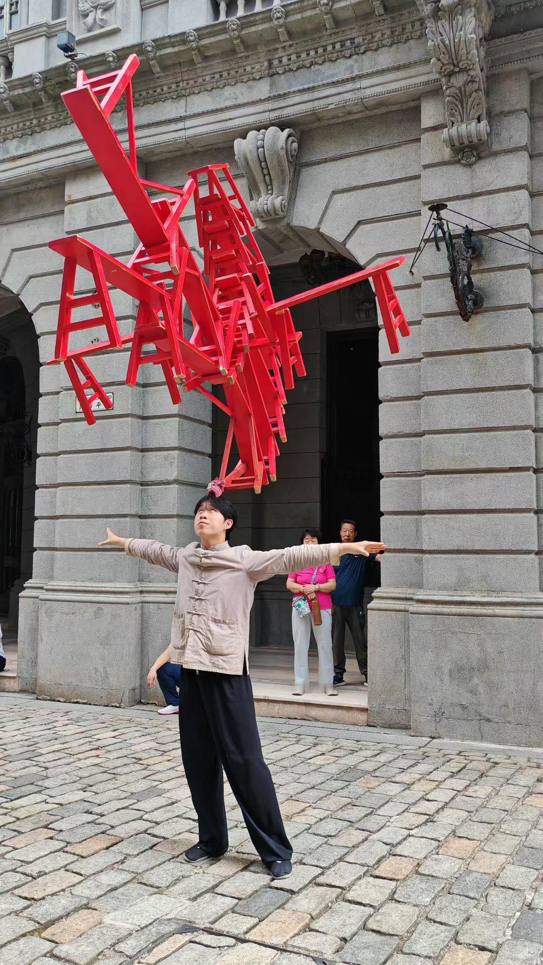 晒图笔记大赛在百年石墙前，他用平衡与勇气，把寻常的红椅叠成了一座向上生长的火焰雕