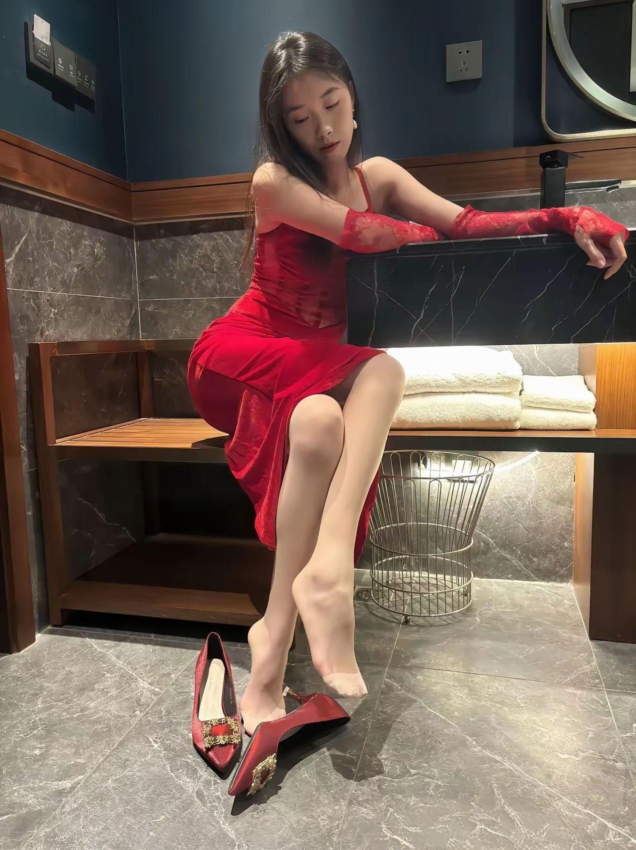 穿着红色连衣裙的女士坐在浴室边。