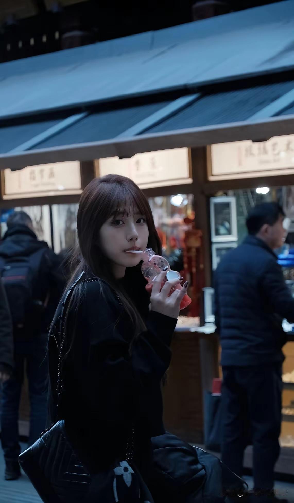 在热闹的夜市中，手持饮料的少女，享受着夜晚的美好时光。