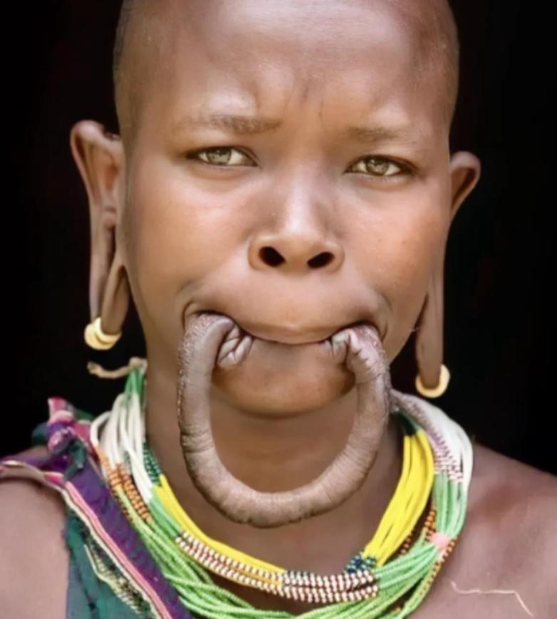 这是一名漂亮的非洲“唇盘族”女孩，她嘴里含着的并不是香肠，而是自己的下嘴唇，女孩
