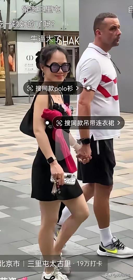 女子和老外牵着手，脸上绽放出幸福的笑容，反观这个老外，表情倒是很严肃的，两个人虽
