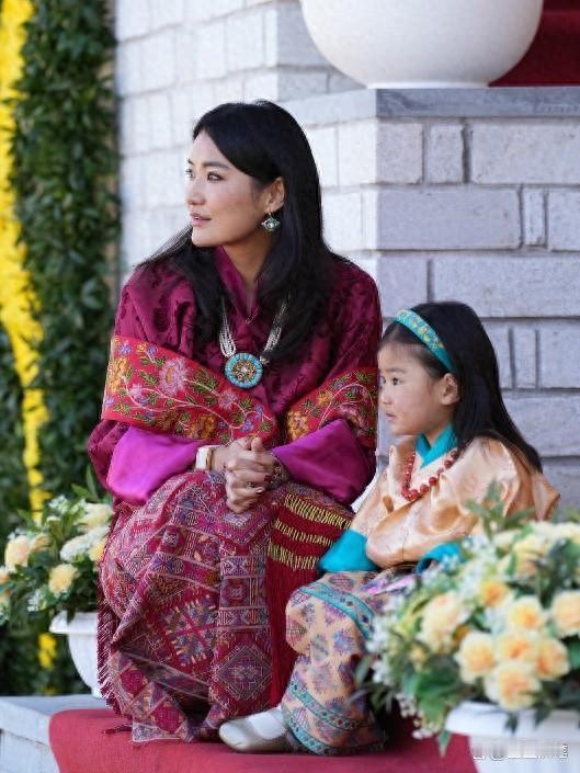 她是不丹王后佩玛，以端庄仪态诠释东方优雅。身着传统织锦与现代剪裁交融的服饰，色彩