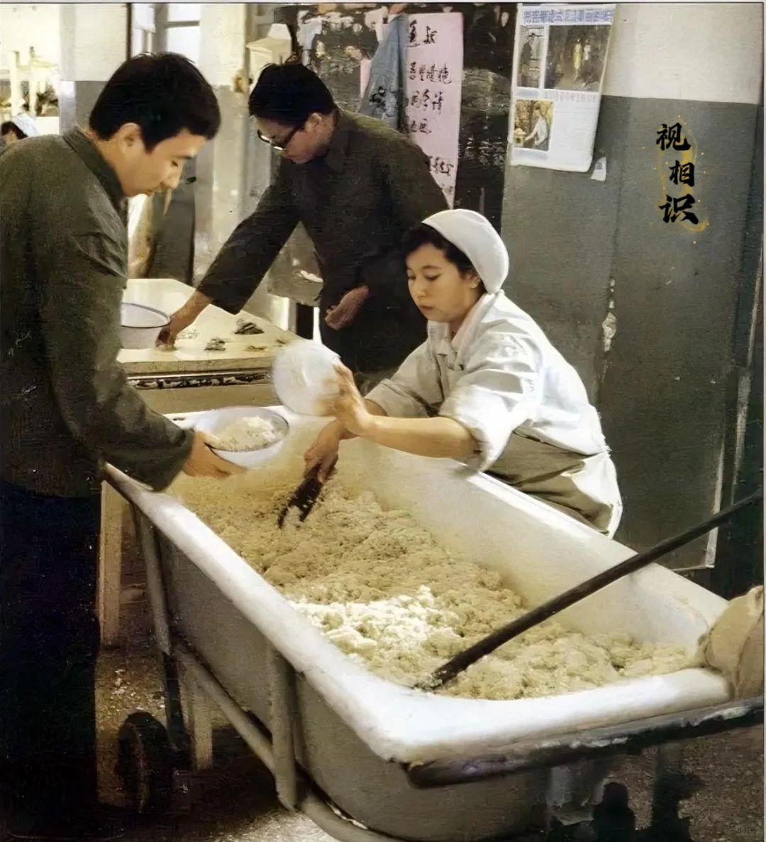 80年代，清华大学食堂的“浴缸”饭盆，镜头中一位工作人员正在给学生打饭，旁边有人...