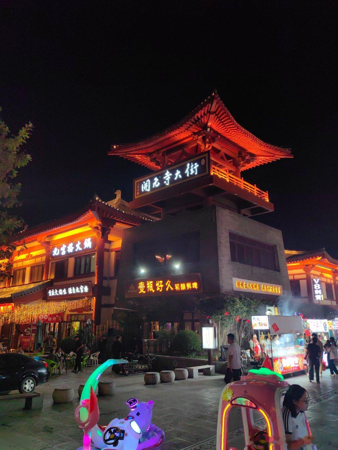 夜幕下的开元寺大街，是一场唐韵与烟火的绝美交响。仿唐建筑的飞檐翘角在灯光里流转着