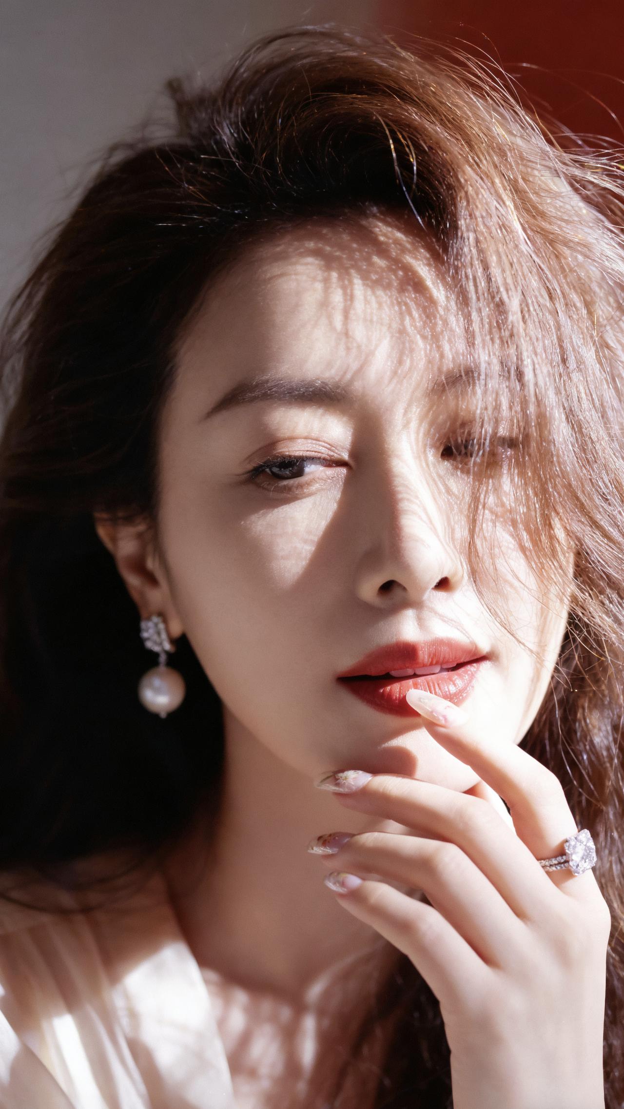 暖光淌过蓬松柔软的发梢，在细腻的脸颊落下绒绒的光斑。红唇轻噙着一点似有若无的笑意