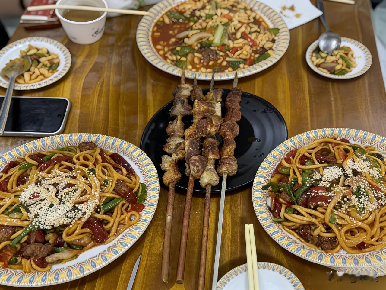 木桌上摆开满满的新疆风味，大盘的炒米粉裹着浓郁的番茄酱汁，撒上白芝麻看着就馋人，