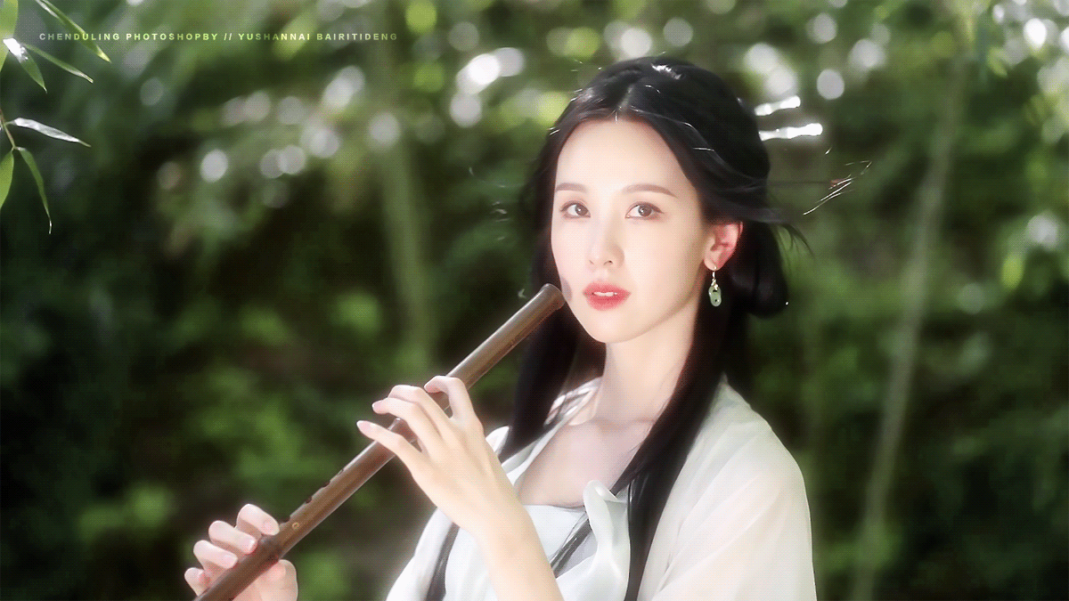 一个美女在绿树丛中吹笛子。