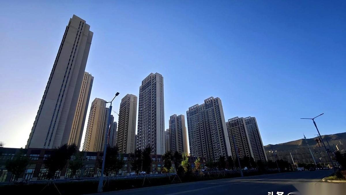 站在工地围挡外，风一吹，铁皮发出沉闷的“哐当”声。
售楼处那幅印着“理想生活”的