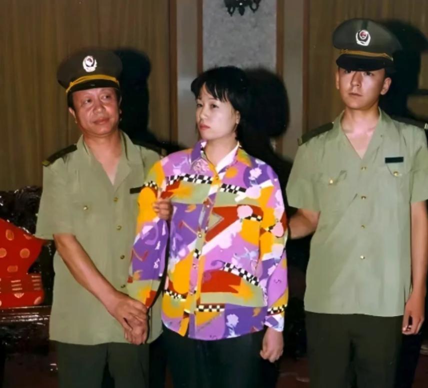 2000年，刘艺霞被判死刑，照片中的她，身穿花衬衫，被两名警察押送着，面无表情，