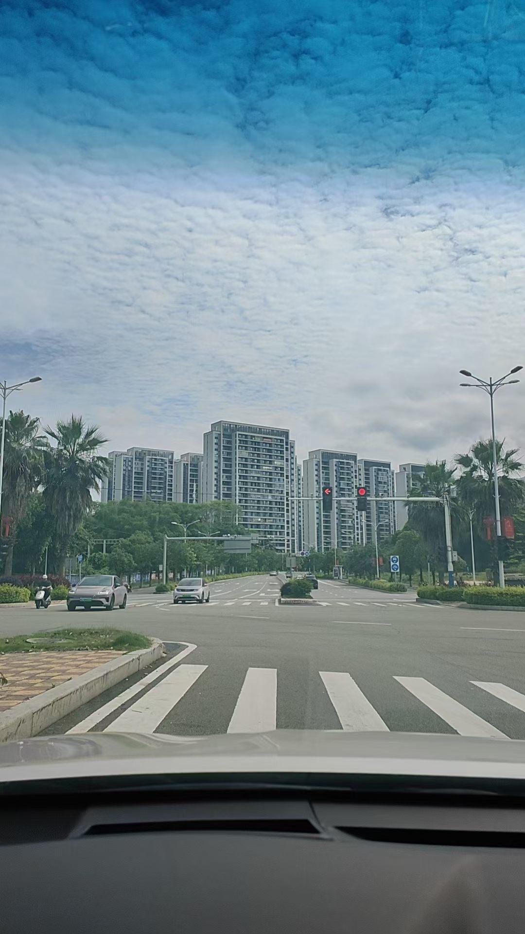 城市街景，车流穿梭，蓝天白云，现代建筑林立。