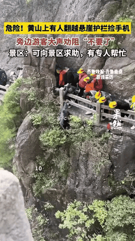 安徽一女子在黄山游玩时，手机掉到悬崖上，她翻出栏杆，让另一名游客拉着自己胳膊，想