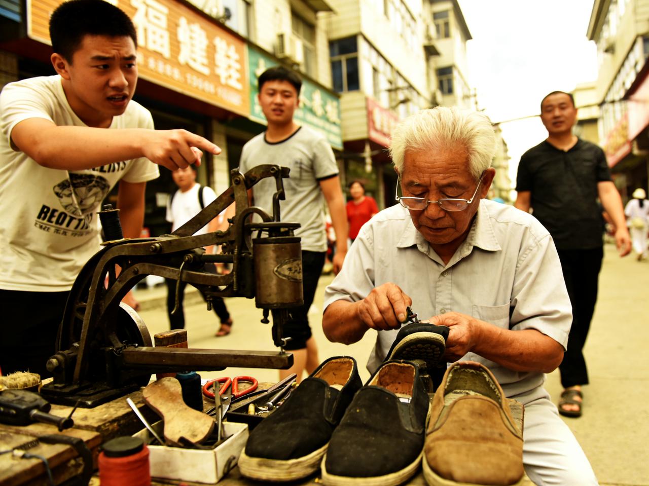 标题：退休教师摆摊修鞋，十年不收分文，有人却说他傻

在市中心的老槐树下，有个修