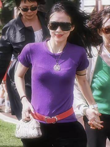 这是2006年时候的章子怡。她佩戴着深色大框墨镜，长发随风飘动，面带微笑，神态轻