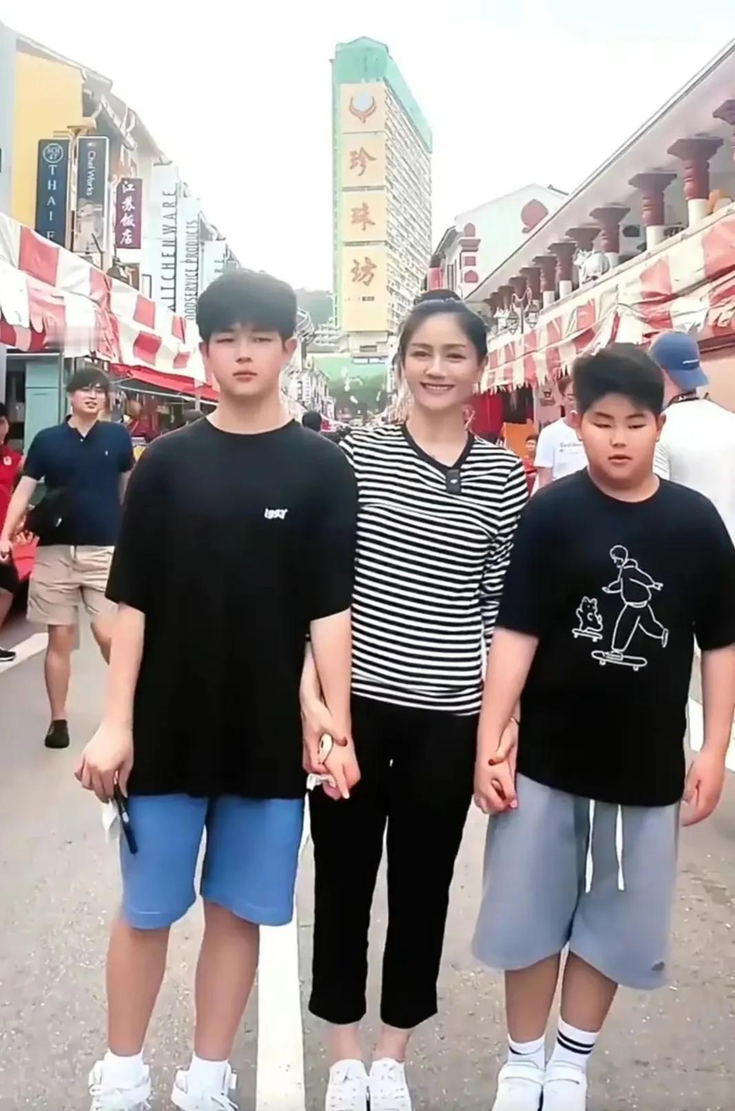 她与两个儿子在一起的合影。
她紧紧拉着两个儿子的手，看得出来非常疼爱儿子。