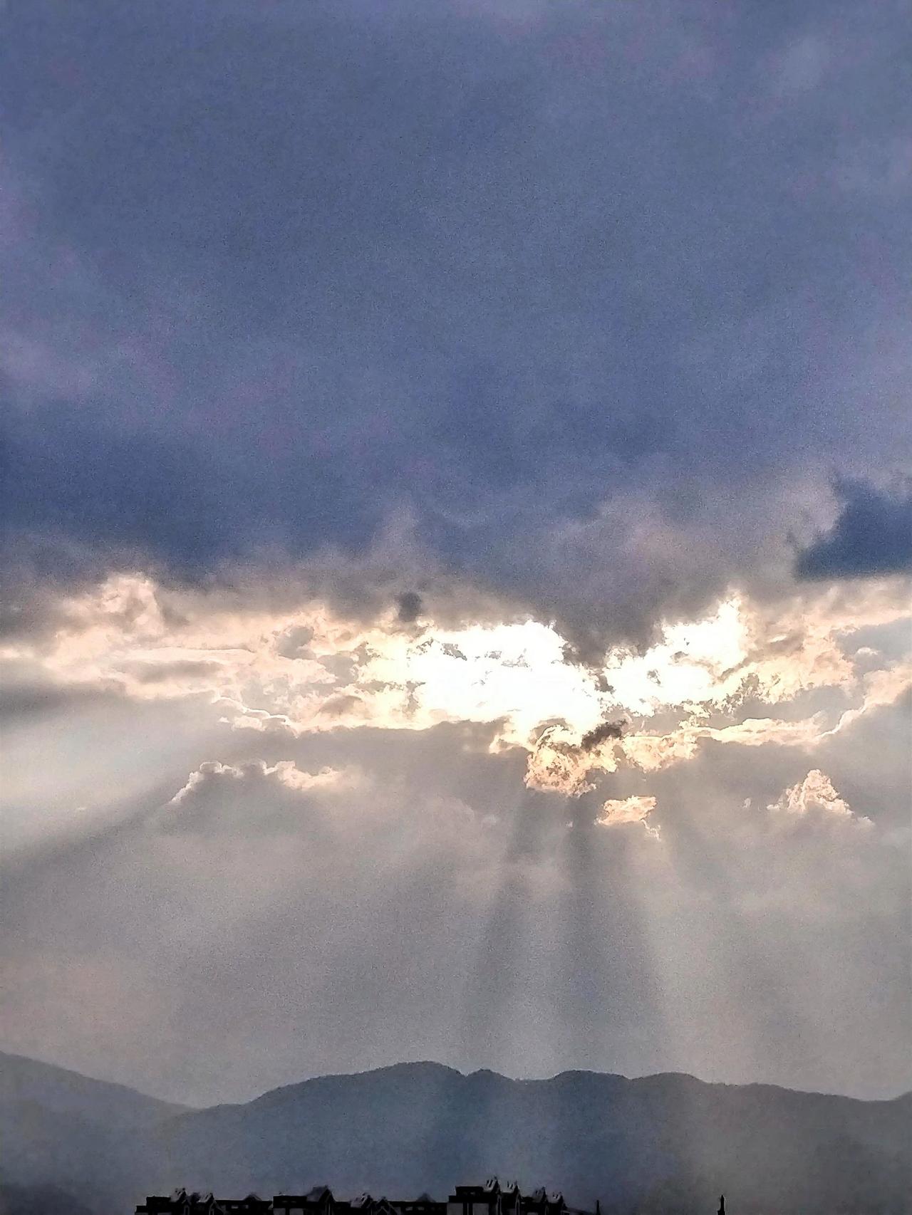 云海翻涌，阳光穿透云层，照亮山峦，宛如仙境。