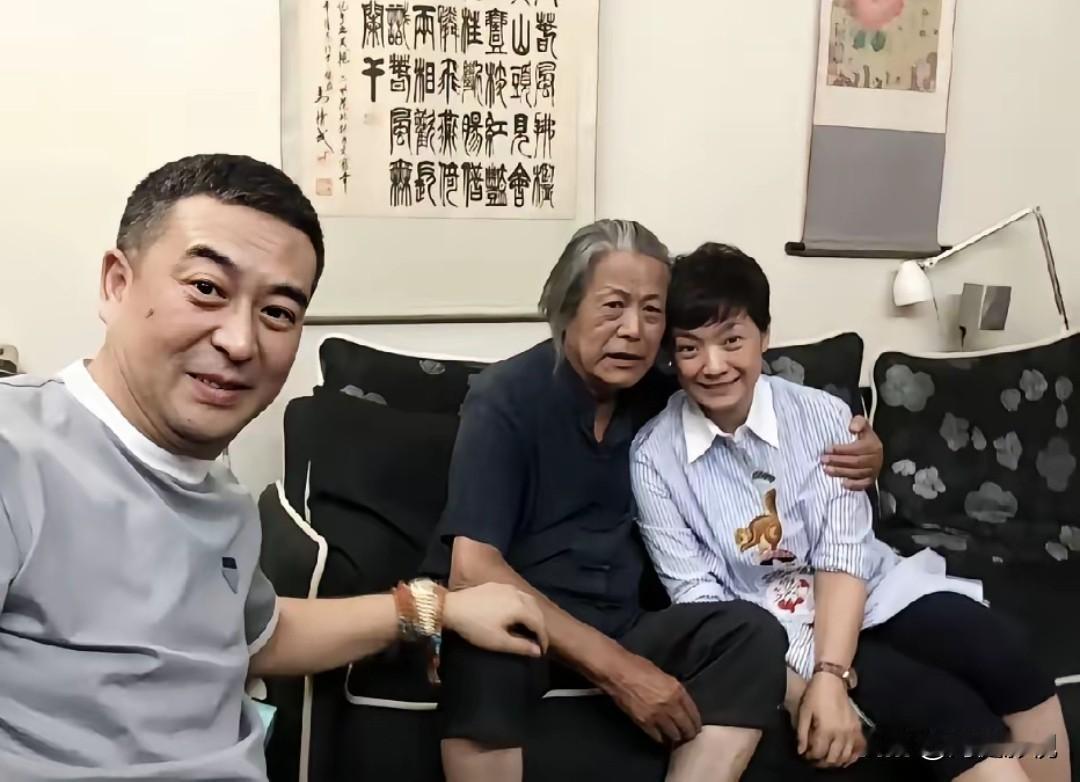 仔细看，左边是气质尔雅的张嘉译，就不知坐沙发上搂着美女是谁？看满脸皱纹，长白发丝