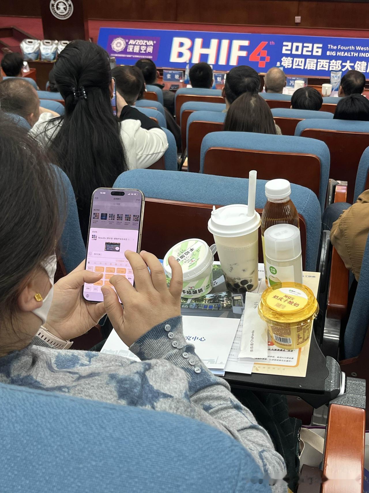开个会，前排这位女士桌上摆满了食品，边吃边玩手机，这显然是对发言人的不尊重。建议