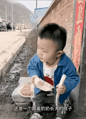 这一看就是奶奶带的孩子，你看他小小年纪，一手拿着一根大葱，一手拿着奶奶刚蒸好的，