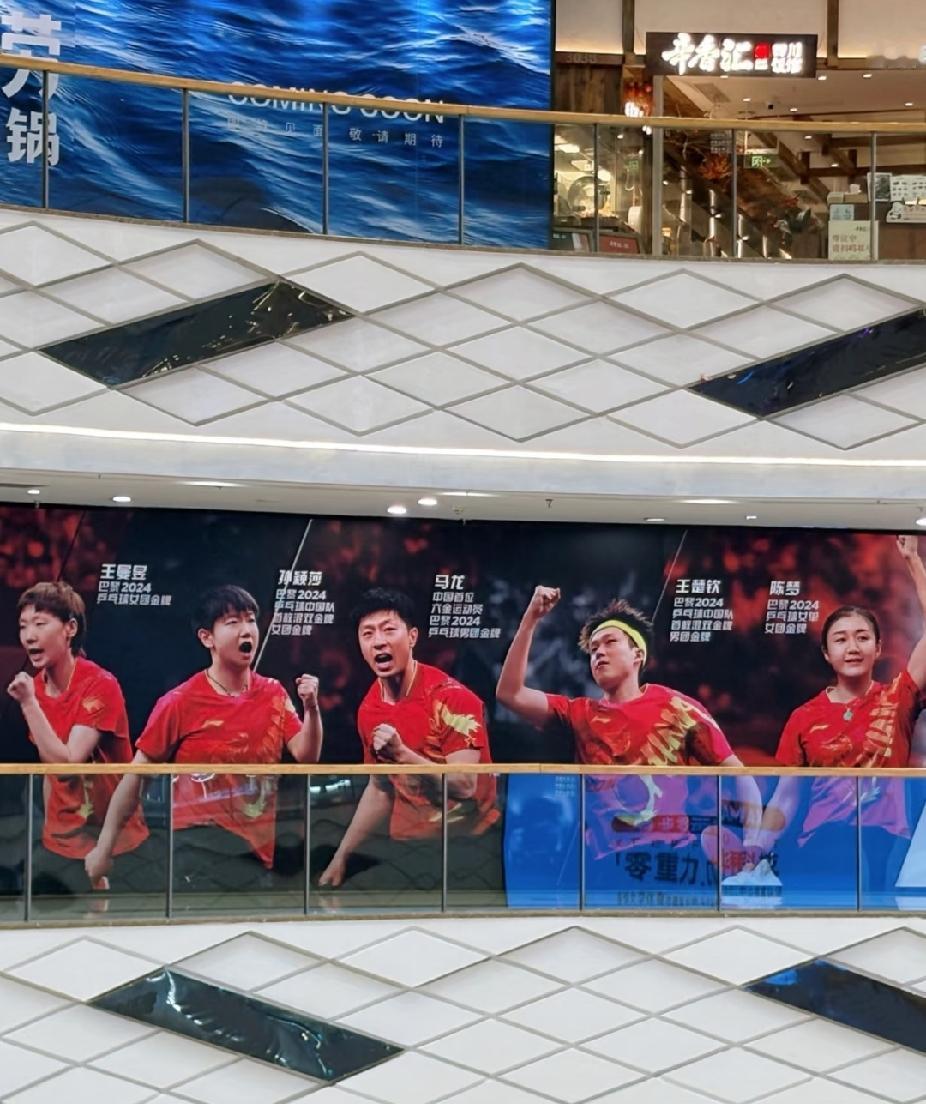 刷到商场里超震撼的一面大屏海报！🥳
一边是咱们国乒的冠军天团，王曼昱、孙颖莎、