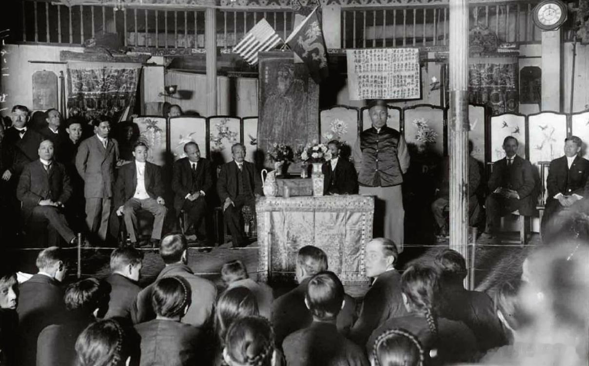 1908年清朝驻美公使伍廷芳（中站者）在纽约华人剧院内向当地华人劝设孔庙，后面挂