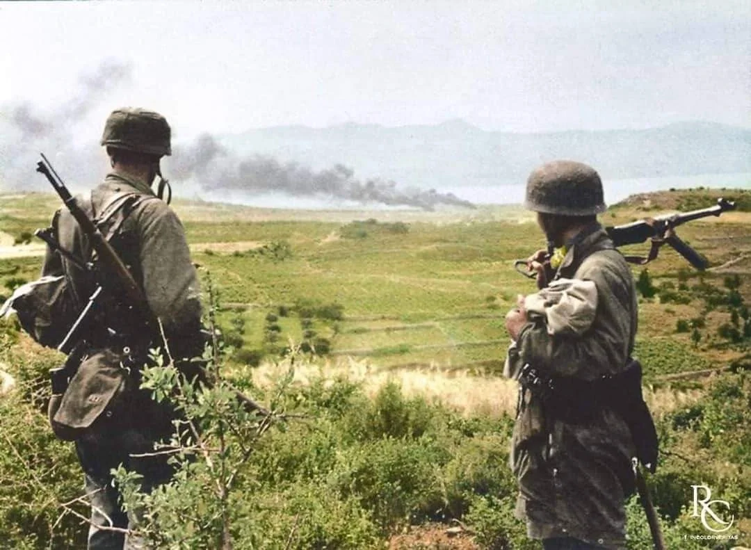 1941年5月，德国第三伞兵团第一营的两名伞兵在山顶上俯瞰克里特岛远处...