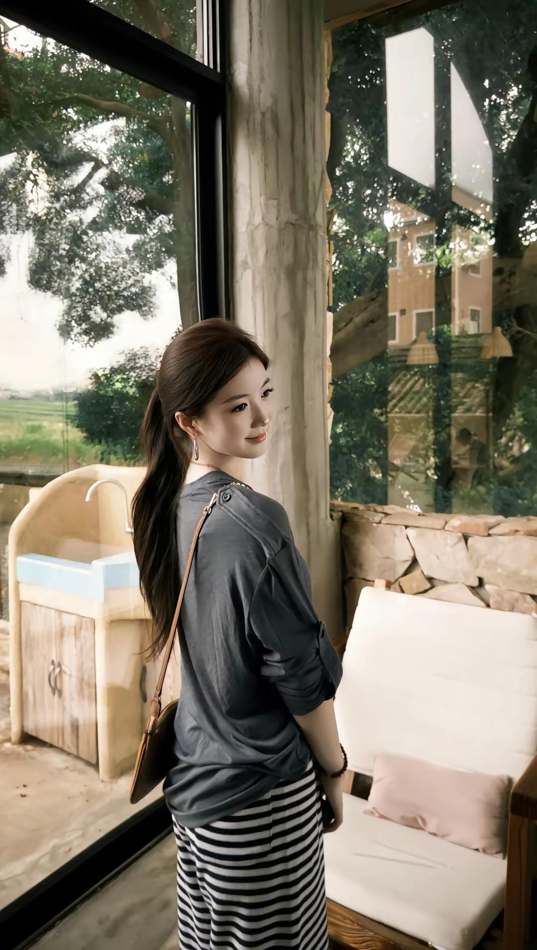 女孩站在窗边，看着外面的风景。