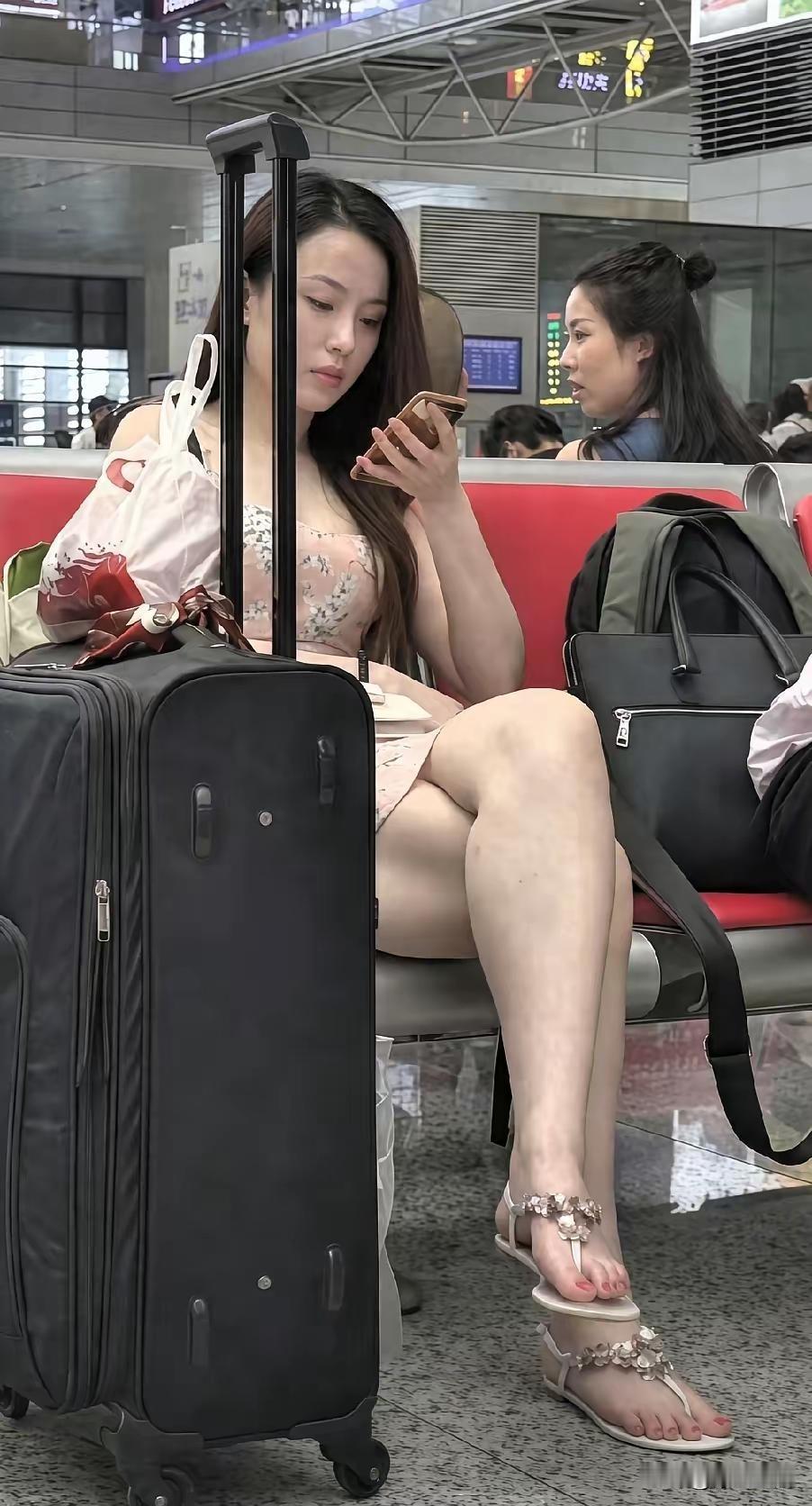 这般气质佳人，本该坐在办公室享受清凉，想不到外出奔波。身旁立着黑色行李箱，想来应