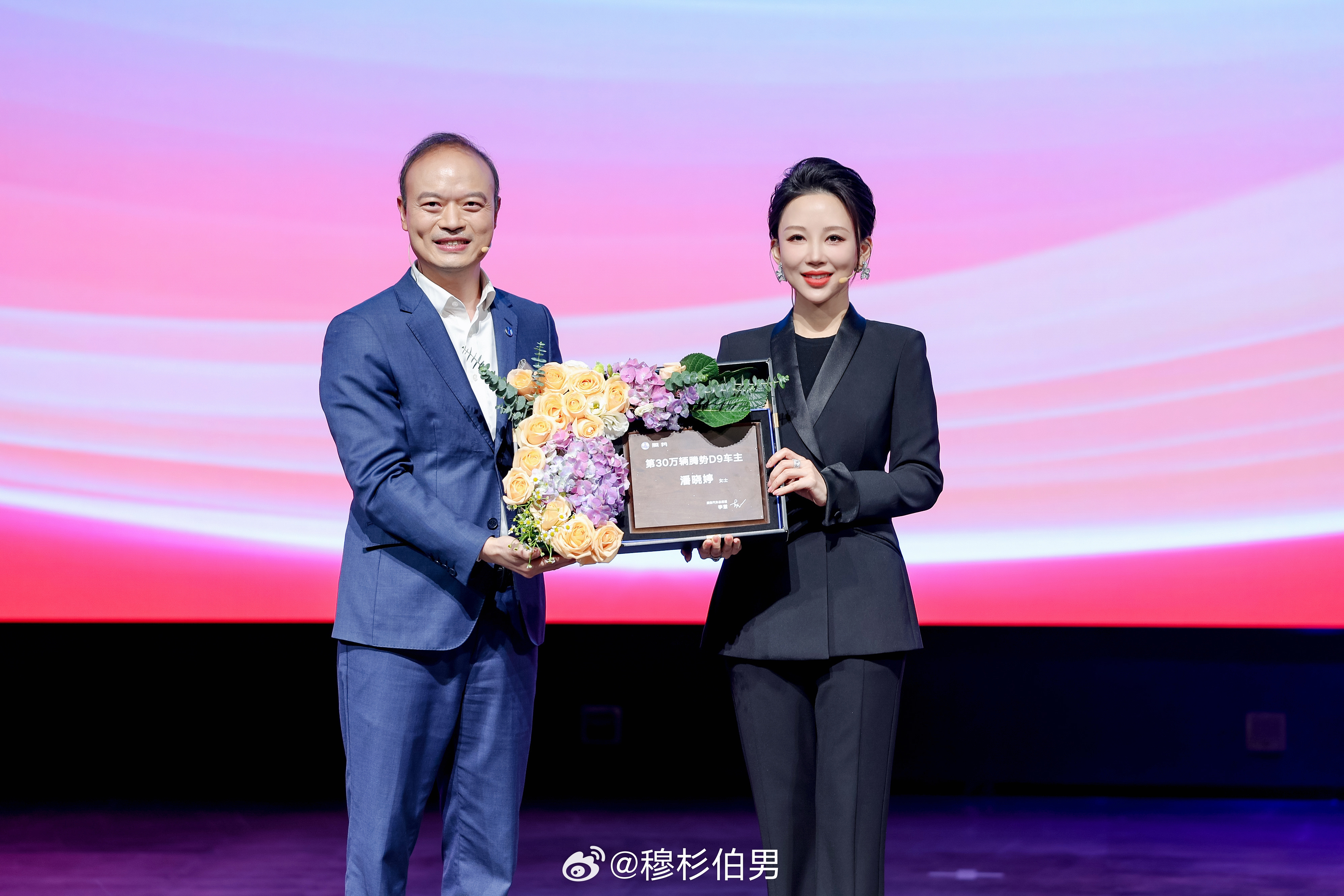 腾势D9在郑赛迎来了第30万位车主，李慧总亲自把一台紫金双拼的钥匙交到潘晓婷手里