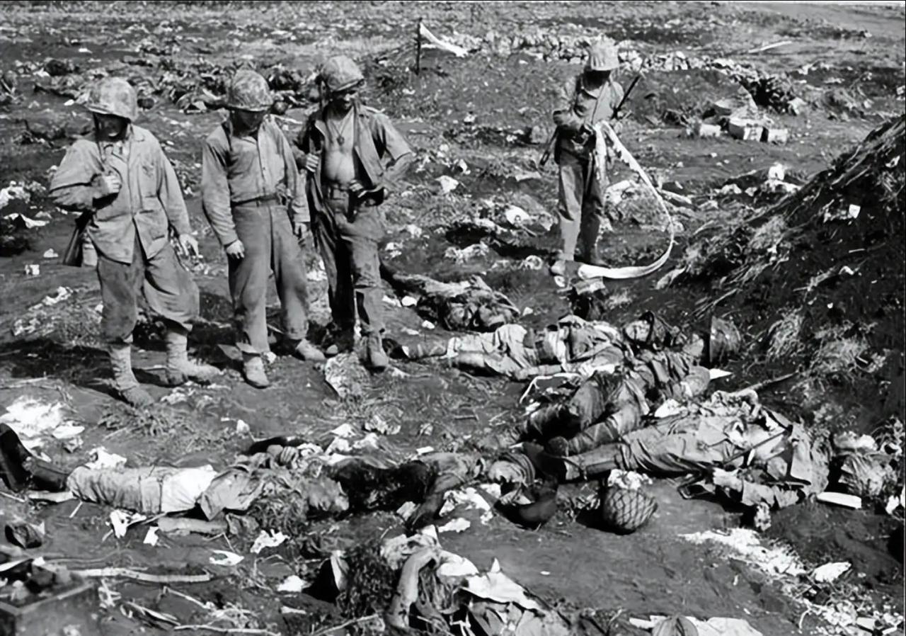 这张黑白照片拍摄于1944年塞班岛战役结束后，记录了美军士兵在战场上查看日军尸体