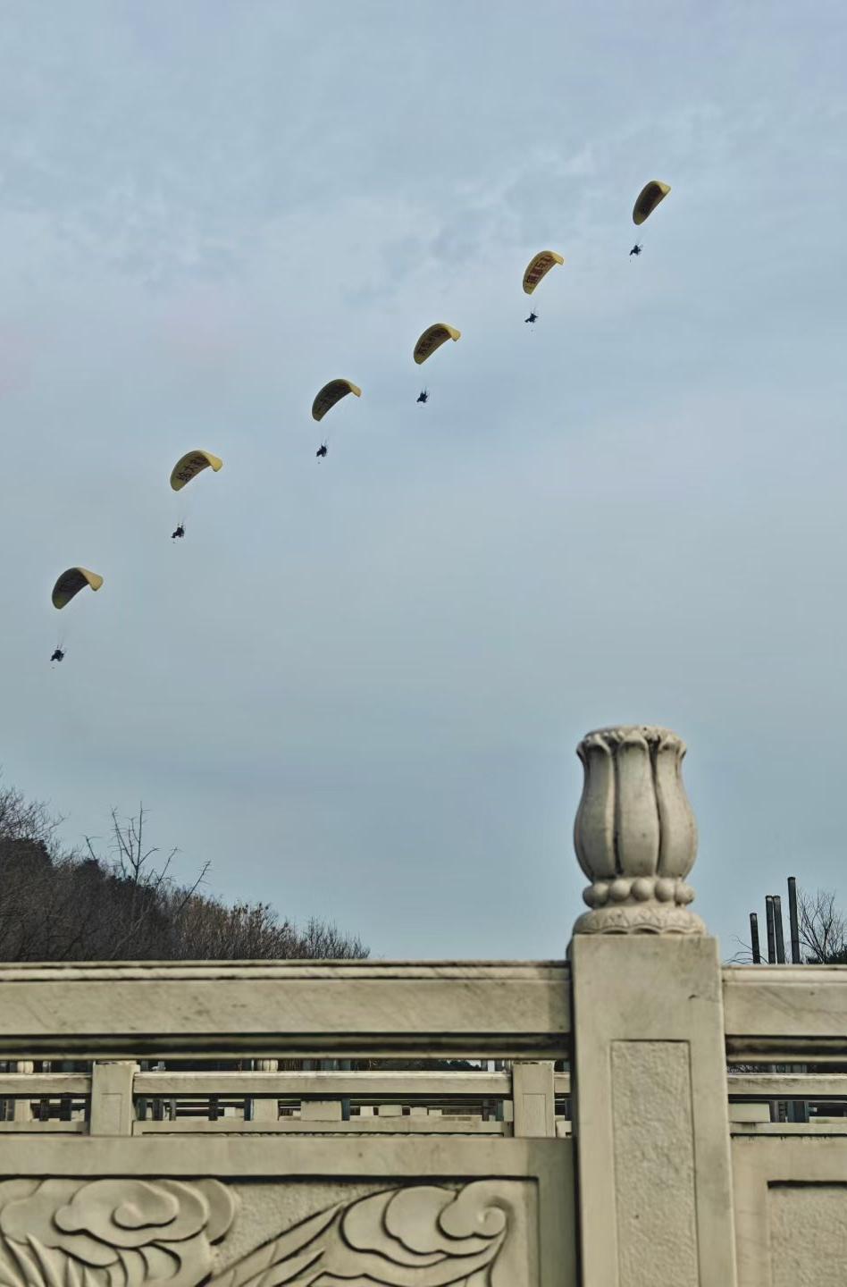新年爱好打卡六伞齐飞，划破浅灰的天际。石栏上的云纹还凝着古意，空中的黄翼已载着风