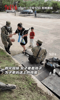 近日，吉林敦化救灾现场子弟兵坐在大树下短暂休息，女子带着儿子走了过来，本以为她是