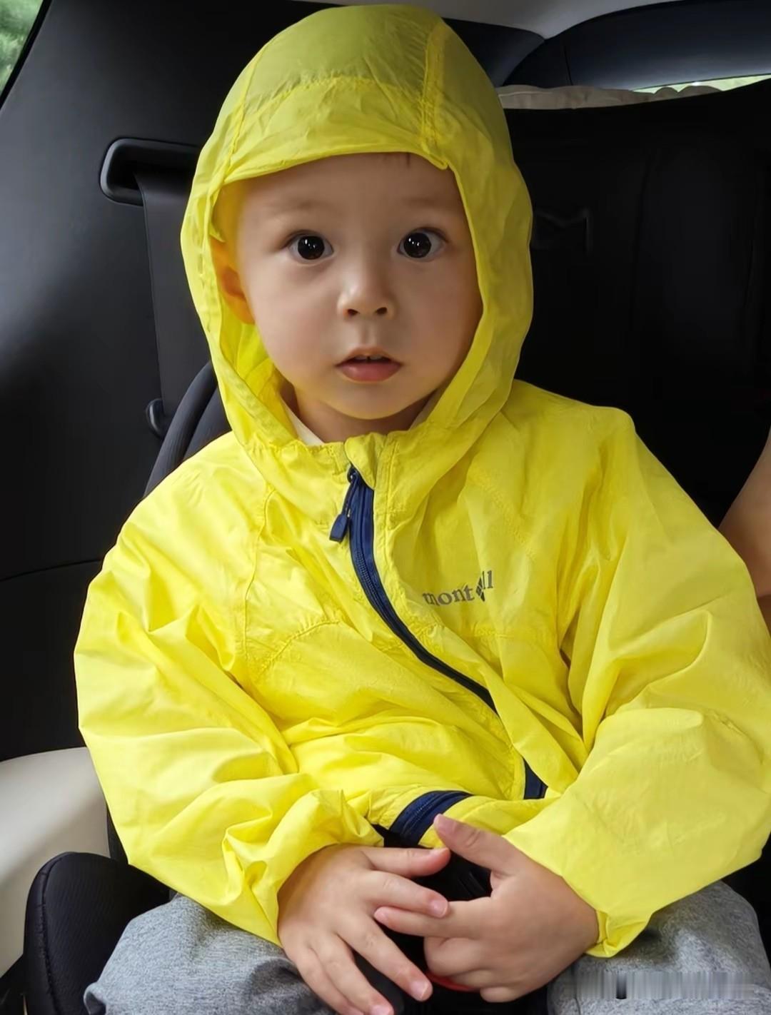 叶海洋家的欧森和欧文去上幼儿园的路上，弟弟坐在车上，手里紧握阿贝贝，他笑容满面，