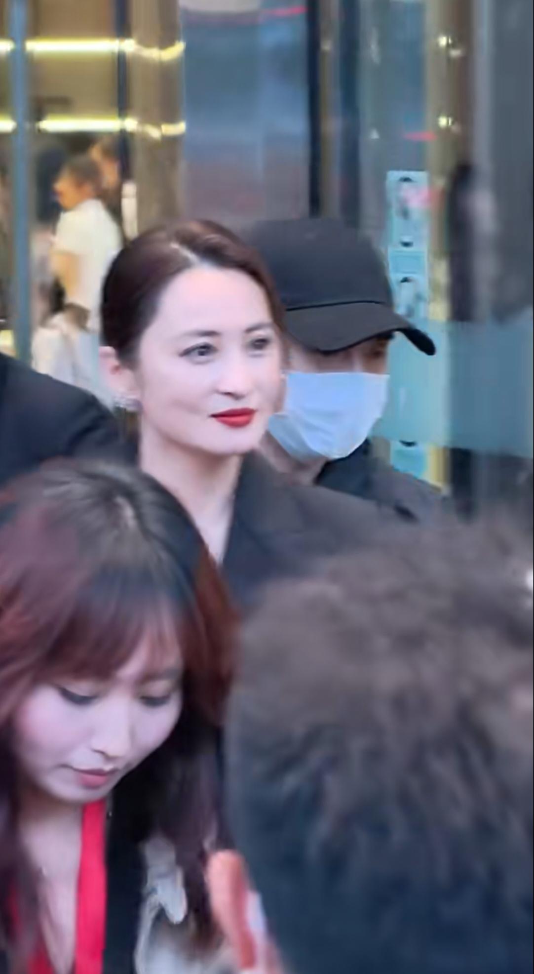 蒋勤勤线下活动的路人抓拍，周围挤满粉丝，她主动挥手致意，眉眼柔和带笑意，待人亲和