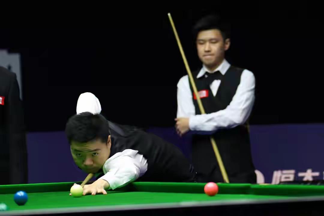 选手专注打球，旁边裁判在旁观看。两位都是中国顶级选手，他俩的这场比赛可能要打破收