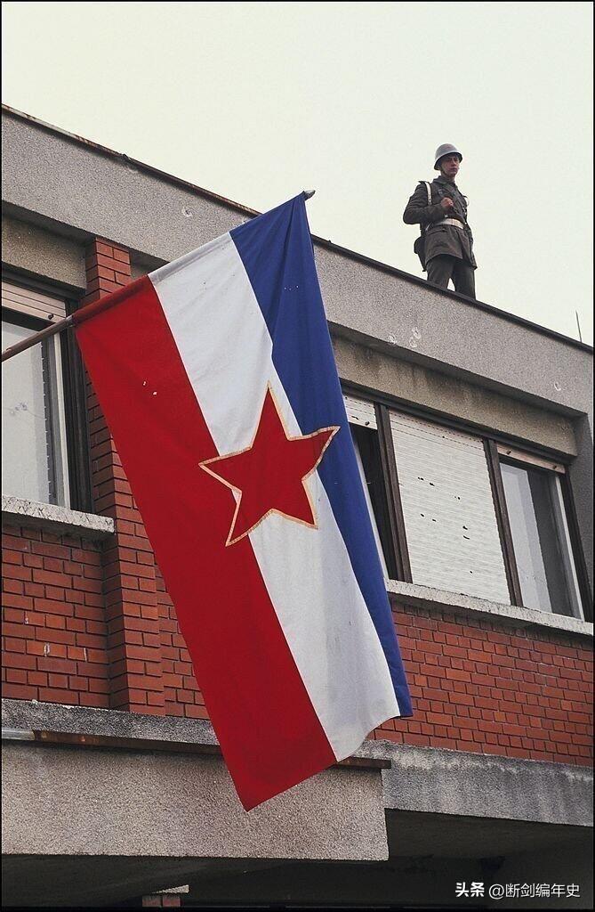 南斯拉夫解体的阵痛。一面即将被取代的社会主义旗帜，一个在屋顶警戒的士兵，还有建筑