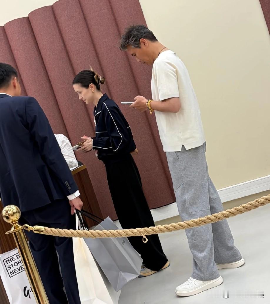 演员李乃文带老婆巴黎购物，夫妻俩收获不小买了不少东西，买单时，他站在后面玩手机，