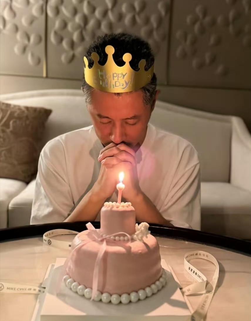 任重发文庆祝46岁生日，晒出自己戴着生日帽虔诚地对着粉色蛋糕许愿，两鬓有许多白发