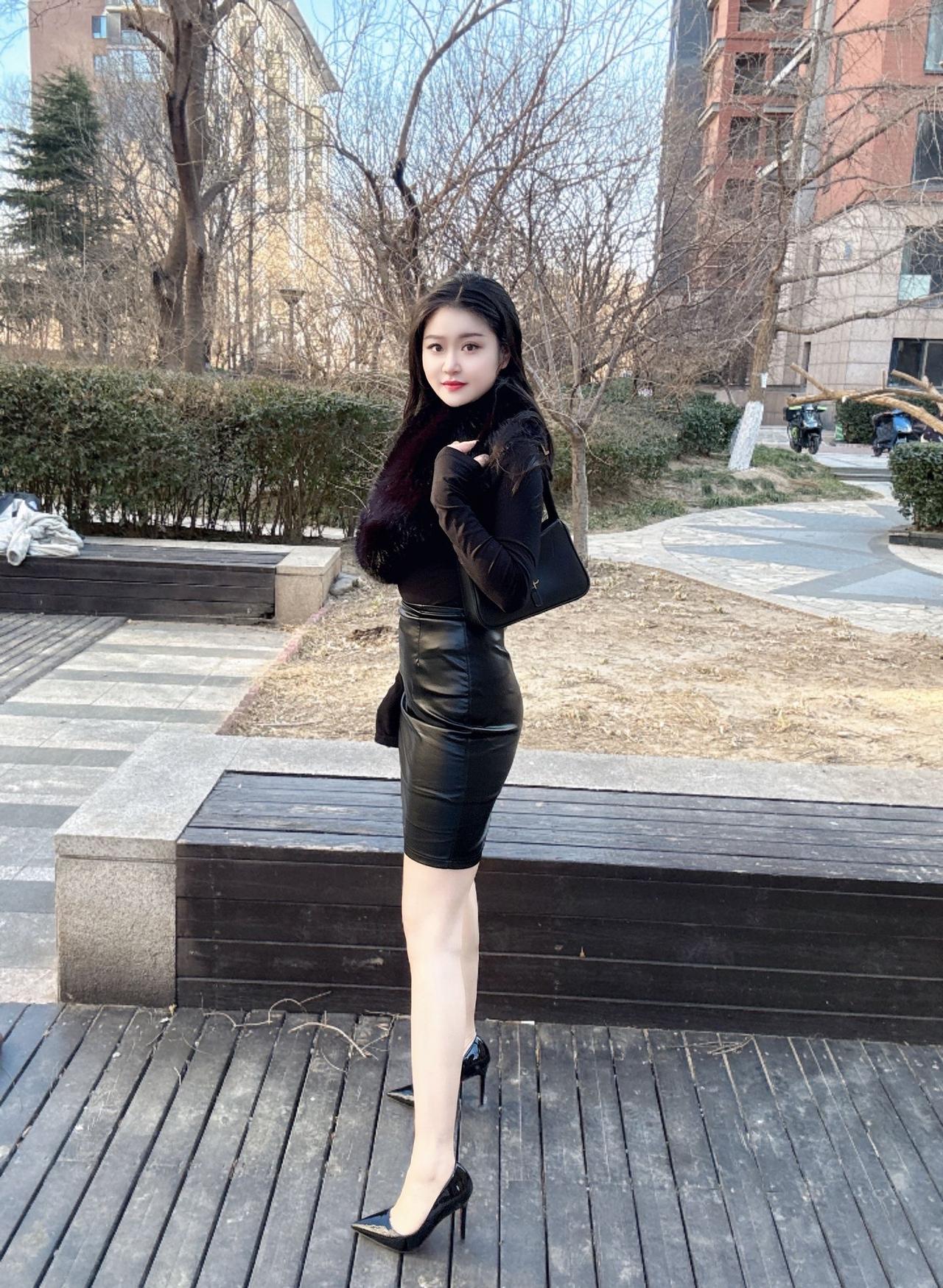 冬日暖阳下的时尚都市女郎，黑色皮裙与毛绒外套的完美搭配，尽显优雅与自信。