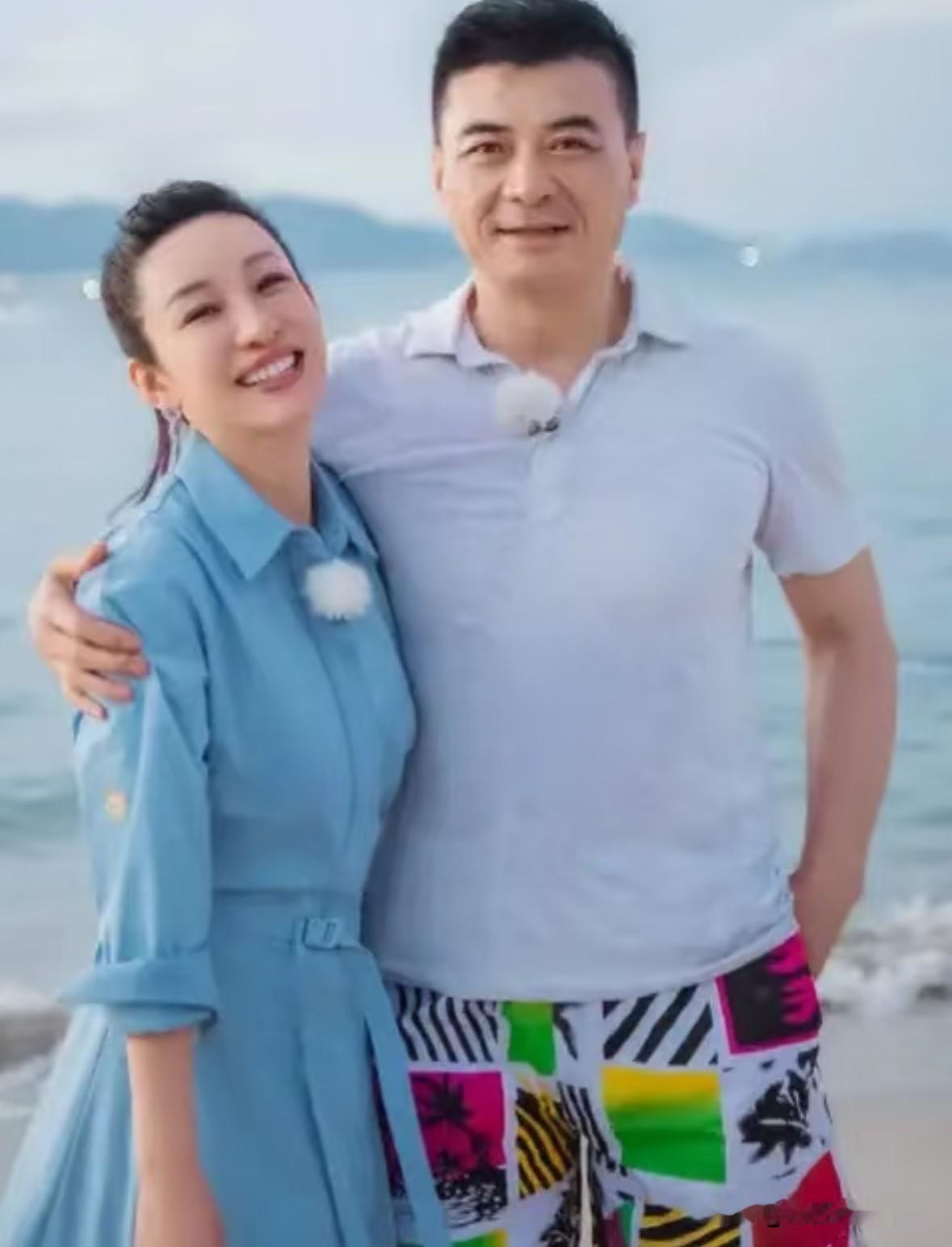 阳光帅气的王新军右手搭在笑容满面的妻子秦海璐肩上，在海边拍摄的一张合影。
他们是