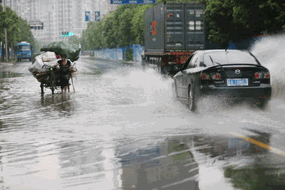 这是发生在广州街头的一幕。
一场大雨过后，道路上积满了雨水，一位收废品的阿姨卷着