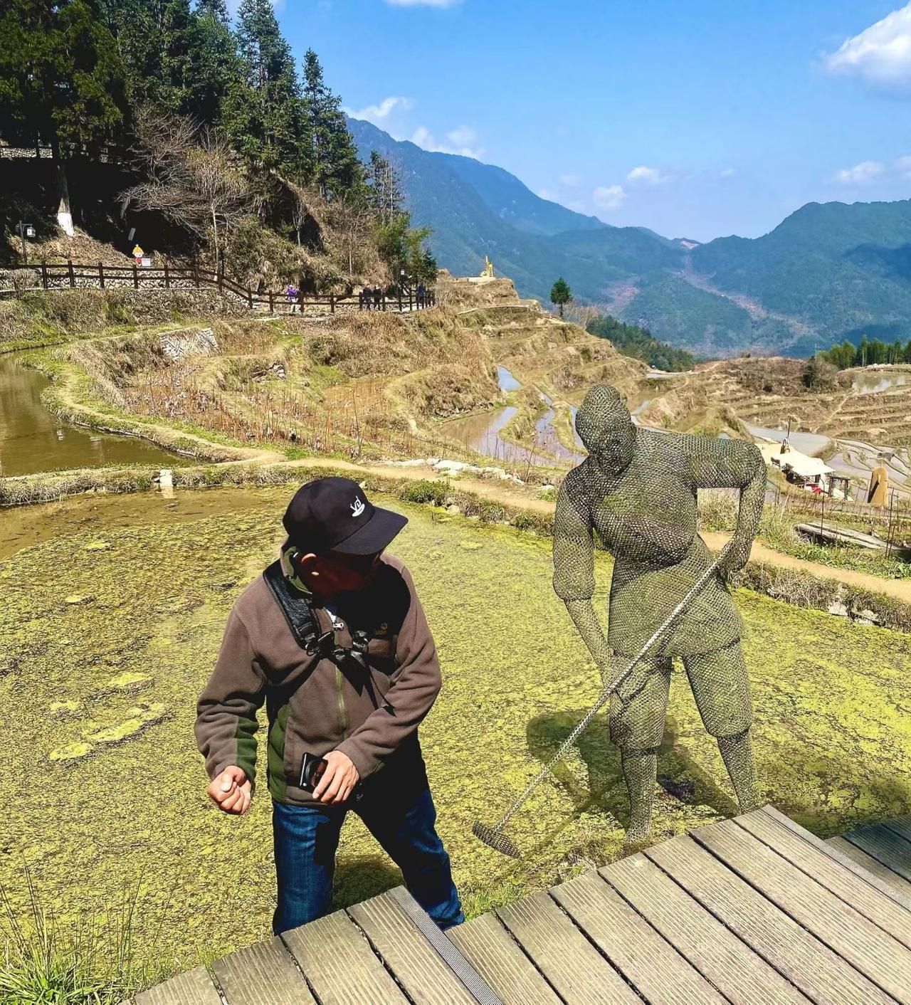 梯田浸着春水，泛着苔绿的光，铁艺耕者似与远山共守农时，连风里都漫着春耕的诗意。